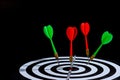 Red and green dart arrow hitting target center is Dart board Isolated on black background Royalty Free Stock Photo