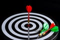 Red and green dart arrow hitting target center is Dart board Isolated on black background Royalty Free Stock Photo