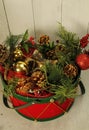 Red/green drum basket filled with evergreen branches, poinsettia flower,s pine cones, red/gold Christmas balls, Royalty Free Stock Photo