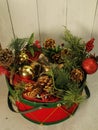 Red/green drum basket filled evergreen branches, poinsettia flowers, red/gold Christmas balls, jingle bell balls, pine cones Royalty Free Stock Photo