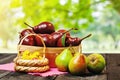 Red and green fresh pears in a wooden basket on a dark wooden table in the background of the garden. Easter basket with ciphers in