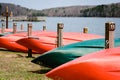 Red and green kayaks on a lakeshore waiting to be rented