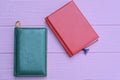 red and green leather notebooks lie on a pink table