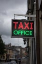 Red and green neon Taxi office sign. Bright neon lights advertising taxis Royalty Free Stock Photo