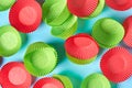 Red and green paper molds for baking muffins scattered on blue desk on kitchen. Top view