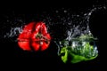 Red and green peppers falling into water, on black background Royalty Free Stock Photo