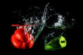 Red and green peppers falling into water, on black background Royalty Free Stock Photo