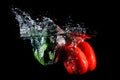 Red and green peppers falling into water, on black background Royalty Free Stock Photo