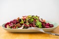 Red and green salad, sliced beetroot, tofu cube and walnut on oval plate, fork