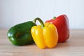 Red, green and yellow bell peppers on wooden background Royalty Free Stock Photo