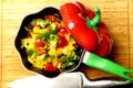 red green and yellow peppers in a pot on wooden background. cooking or gastronomy concept.flat lay Royalty Free Stock Photo