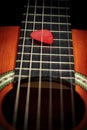 Red Guitar Pick Between the Strings of an Old Acoustic Guitar