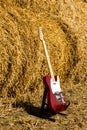 Red guitar telecaster on a straw stack background in a summer day