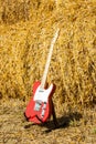 Red guitar telecaster on a straw stack background in a summer day