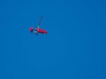 Red gyroplane flies in the blue cloudless sky