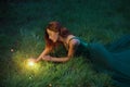 Red hair charming woman is lying on the grass in a wonderful emerald dress with long train Royalty Free Stock Photo