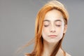 Red hair girl with eyes closed. Studio portrait on gray background