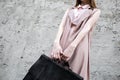 Red hair girl in pink look, with black leather bag, pose on the concrette background. Royalty Free Stock Photo