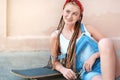 Red hair teenage girl with freckles in casual style with skateboard in summer day on the street