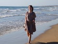 A red-haired barefoot teenage girl walks along the seashore along the water`s edge Royalty Free Stock Photo