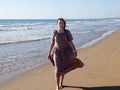 A red-haired barefoot teenage girl walks along the seashore along the water`s edge Royalty Free Stock Photo