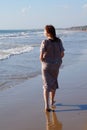 A red-haired barefoot teenage girl walks along the seashore along the water`s edge Royalty Free Stock Photo