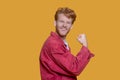 Red-haired bearded young man in red jacket feeling strong