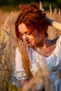 red-haired beautiful girl sits with her back in black, long dress in the grass Royalty Free Stock Photo