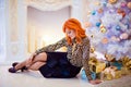 Red-haired beautiful woman sitting near the fireplace and white Royalty Free Stock Photo