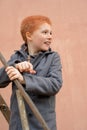 Red-haired boy in a grey coat climbed the rusty metal ladder to Royalty Free Stock Photo