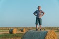 A red-haired boy stands on top of a straw bale on a wheat field Royalty Free Stock Photo