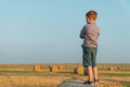 A red-haired boy stands on top of a straw bale on a wheat field Royalty Free Stock Photo