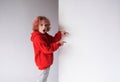 A red-haired boy in a red sweater points his finger at an empty white board, a place for advertising. Royalty Free Stock Photo