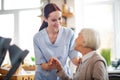 Red-haired caregiver smiling and talking to aged woman Royalty Free Stock Photo