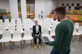 A red-haired Caucasian businesswoman sits in the front row of an empty conference room. Bearded man giving a lecture. Royalty Free Stock Photo