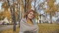 A red-haired, curly-haired girl twirls in the street in the fall.