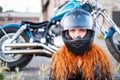 Red-haired curly woman in a helmet near a motorcycle. Royalty Free Stock Photo