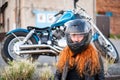 Red-haired curly woman in a helmet near a motorcycle. Royalty Free Stock Photo