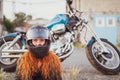 Red-haired curly woman in a helmet near a motorcycle. Royalty Free Stock Photo