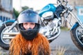 Red-haired curly woman in a helmet near a motorcycle. Royalty Free Stock Photo