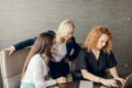 Red haired female corporate mentor helps employees with computer work in office