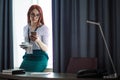 Red-haired female CEO talking on smart phone and drinking coffee. Royalty Free Stock Photo