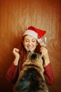 Red-haired female in santa claus hat and fluffy cat.