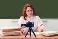 Red-haired female teacher conducts online training of students sitting at the table in the classroom. University classes via the