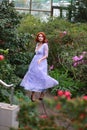 Red-haired girl in arranger where azalea blooms in a colorful flying dress Royalty Free Stock Photo