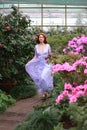 Red-haired girl in arranger where azalea blooms in a colorful flying dress Royalty Free Stock Photo