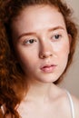 An red-haired girl with brown eyes sprayed thermal water on her face. Sensitive skin care concept. Shot in a studio