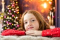 Red-haired girl dreams of near the Christmas tree. smiles, garland, lights, festive, new year, Royalty Free Stock Photo