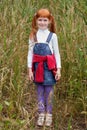 red-haired girl with freckles standing in tall grass