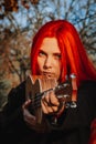 Red-haired girl with long hair plays on the ukulele in the park. School, music education concept, student learns to play the Royalty Free Stock Photo